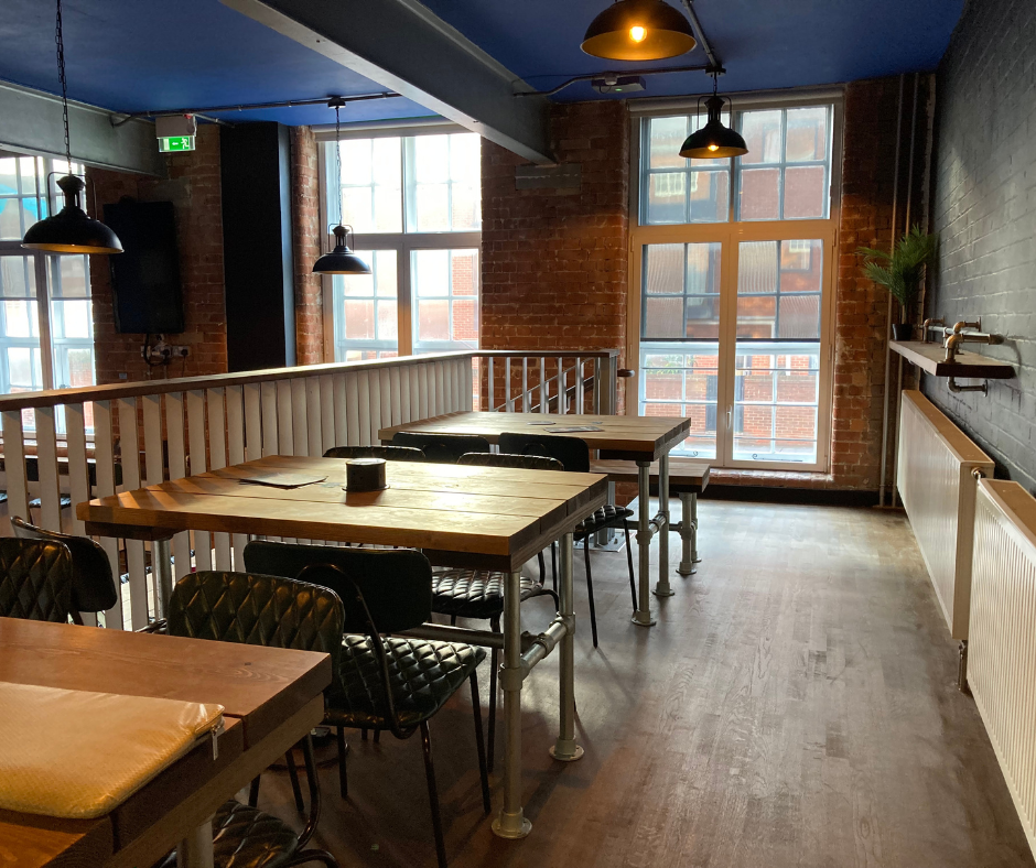 Cafe and bar area at Collective Theatre. With leather green seats and a dark wooden floor and blue ceiling, the space is modern and relaxed.